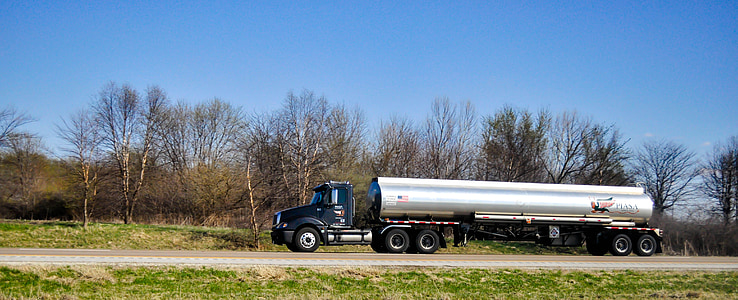 gray and black tanker truck traveling on road at daytime