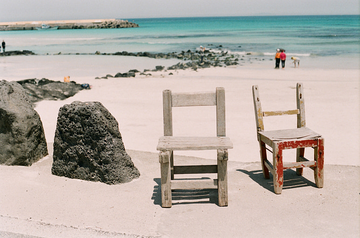 photo of two black wooden chairs near seashore