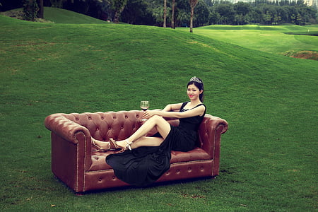 woman wearing black split dress lying on brown Chesterfield sofa