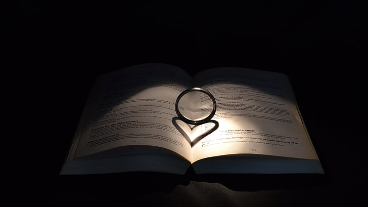 silver-colored ring on top of opened book