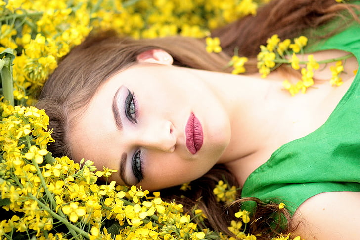 woman in green shirt lying on yellow flower field