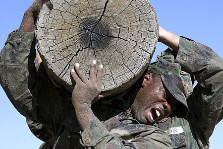 man in soldier uniform carrying wood slab