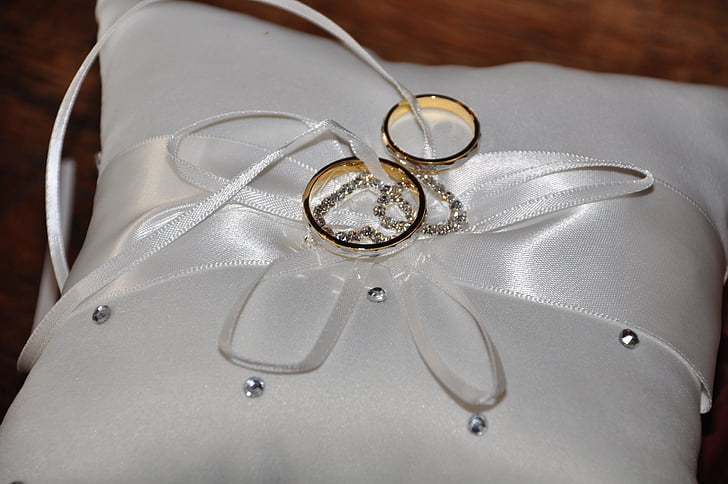 two gold-colored rings on top of white throw pillow