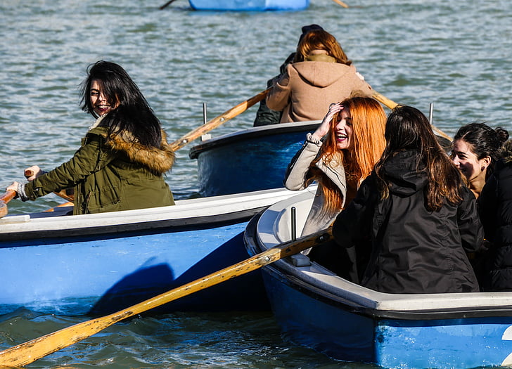 women riding on boat rowing towards each other