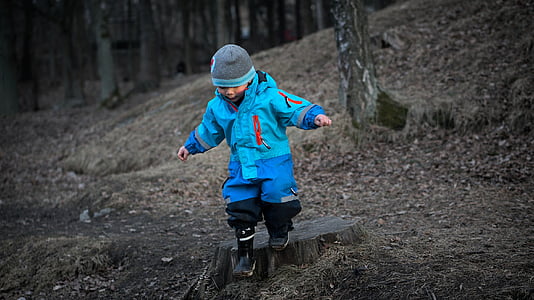photo of boy walking on forest