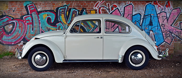 white Volkswagen Beetle parked beside wall