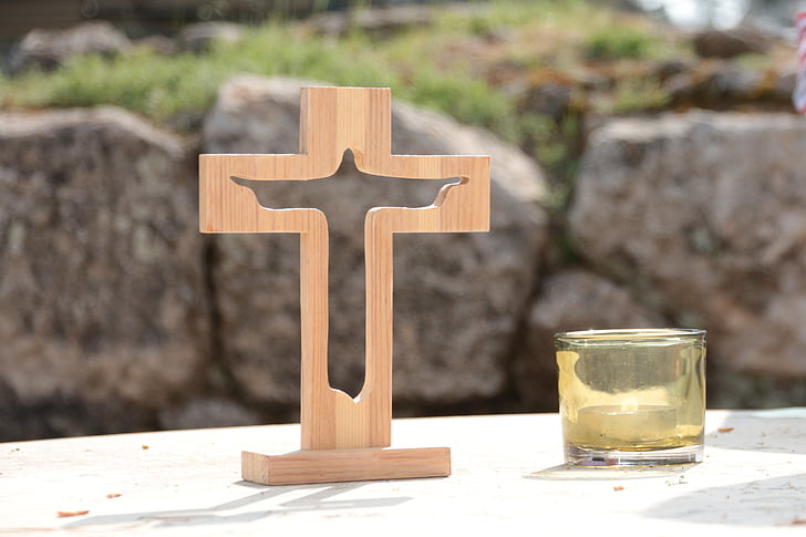 beige wooden cross beside glass candle holder