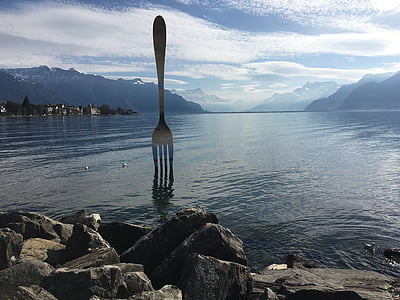 forced perspective photography of stainless steel fork on sea at daytime