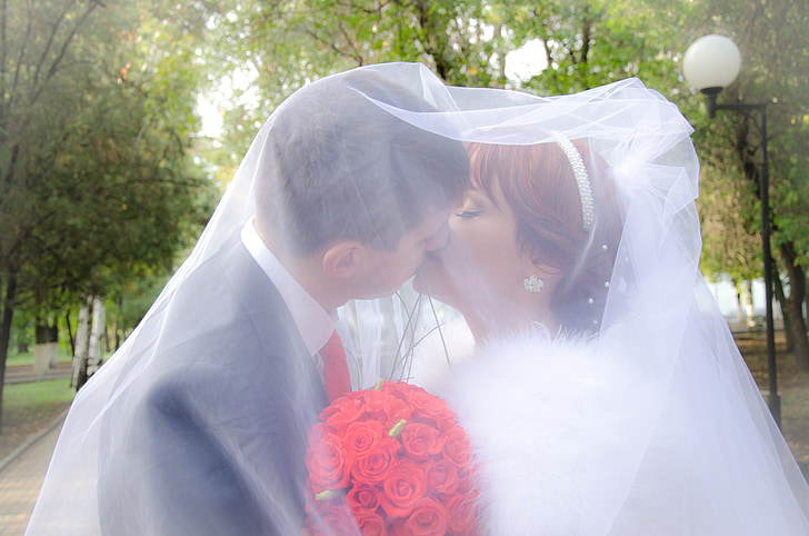 man and woman kissing white in veil