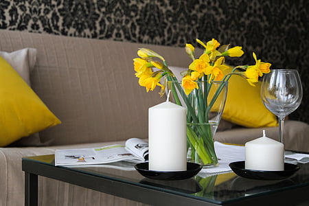 yellow daffodils centerpiece and two white pillar candles closeup photography
