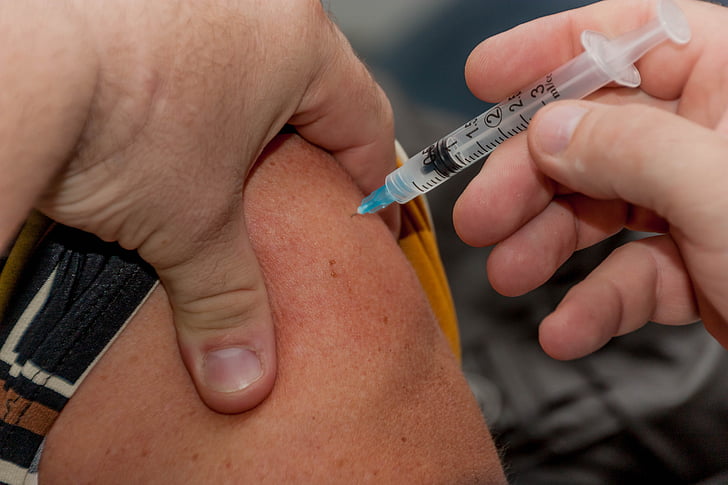 person holding syringe while injected to skin