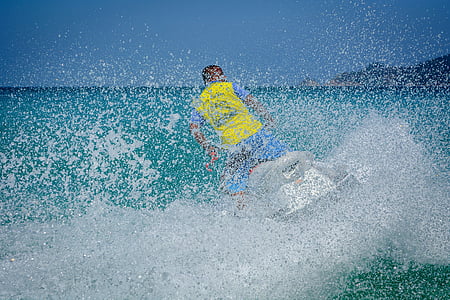 man in yellow and blue riding personal watercraft