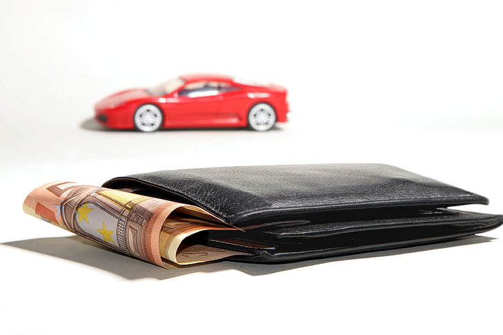 black leather bi-fold wallet with banknotes beside red die-cast toy