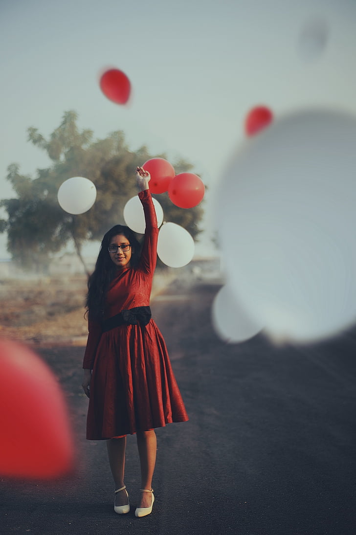 selective focus of woman in red dress holding balloon