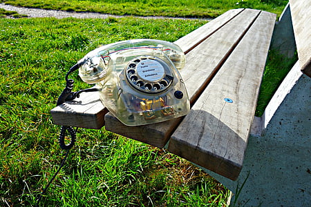 clear rotary phone on wooden bench during daytime