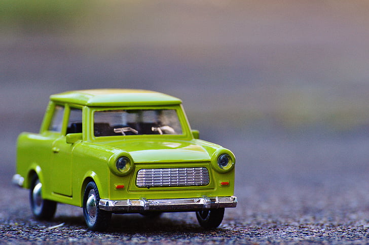 selective focus photography of green car die-cast metal model on concrete road at daytime