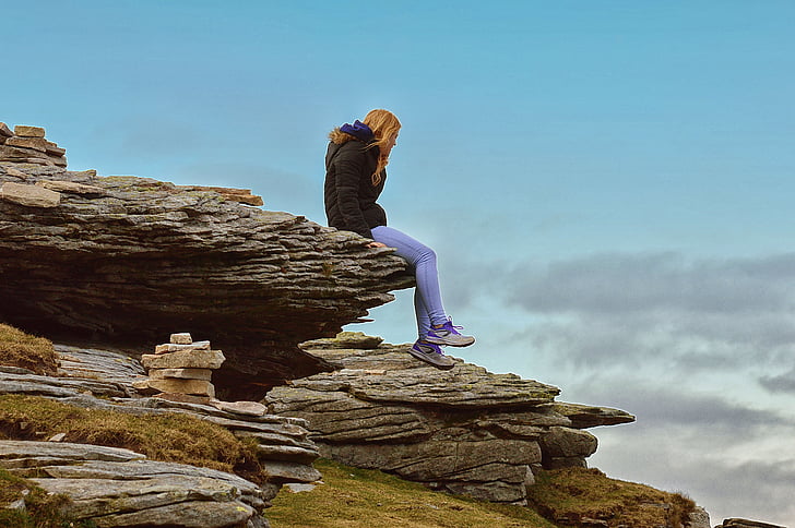 woman sitting on cliff