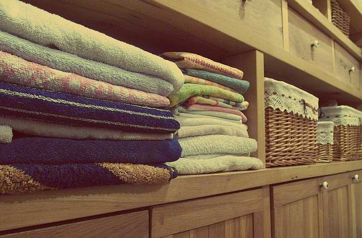 assorted-color towels on wooden shelf