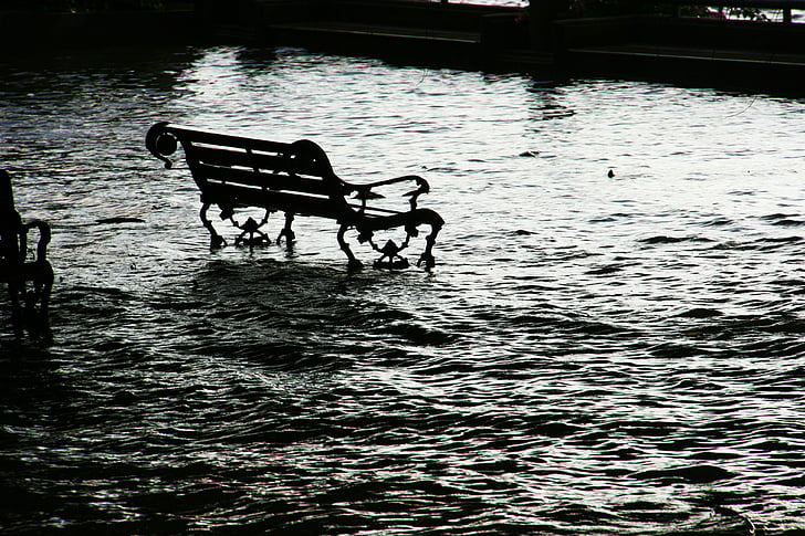 black metal park bench at the middle of body of water