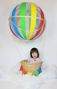 girl with multicolored shirt on brown wicker hot air balloon
