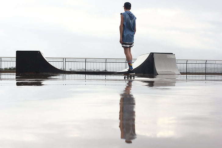 man on skateboard infront rail after the rain