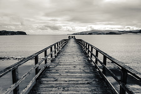 grayscale photo of wooden dock surrounded body of water