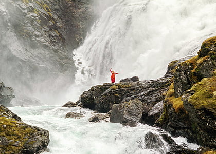person standing on rock surrounded by waterfalls and river during daytime