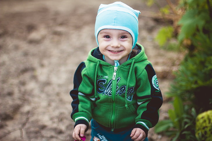 boy in green and black full-zip hoodie wearing blue and white knit cap