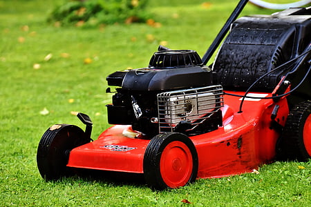 photo of black and red push lawn mower on grass field