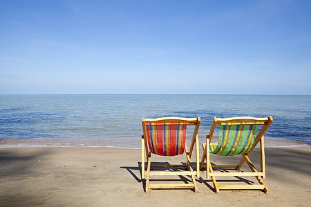 two brown wooden beach chairs on seashore