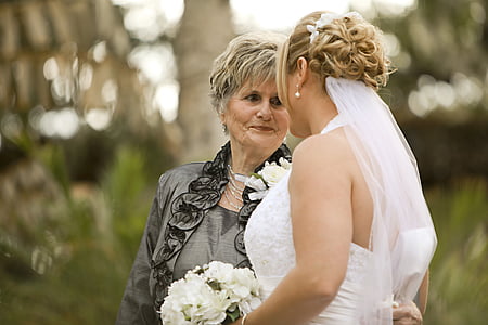 woman wearing wedding dress beside woman wearing gray blazer