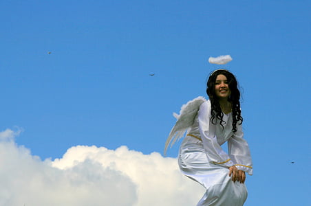 angel sitting on cloud under clear sky
