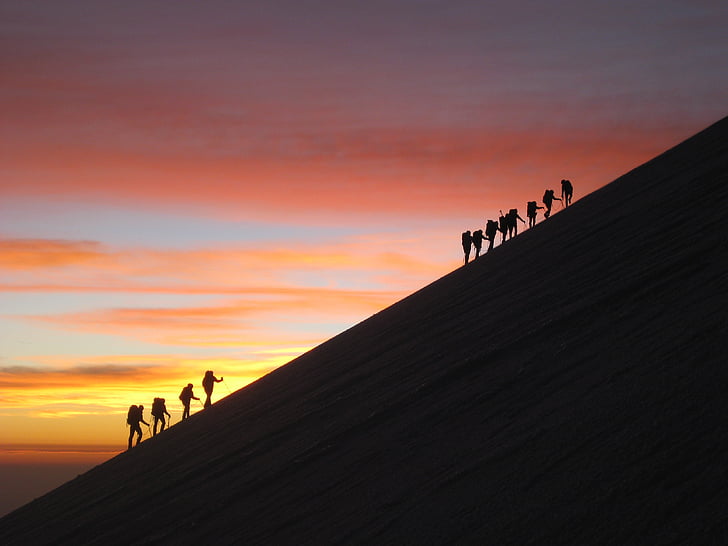 silhouette photo of hikers with background of sunset