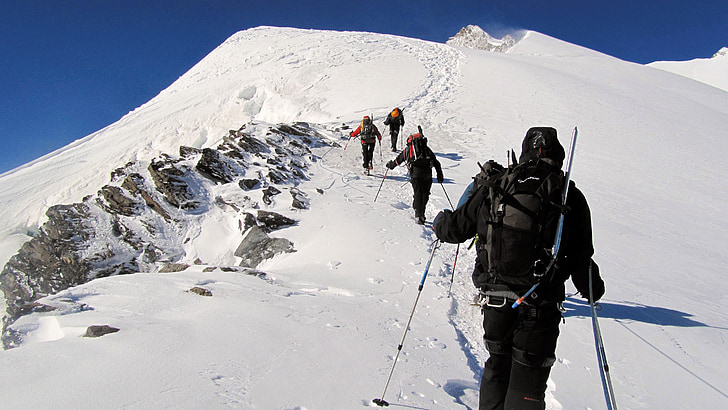 group of people climbing on mountain coated by snow