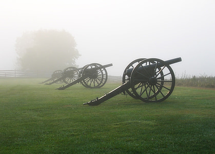 vintage black canons on green grass during foggy season