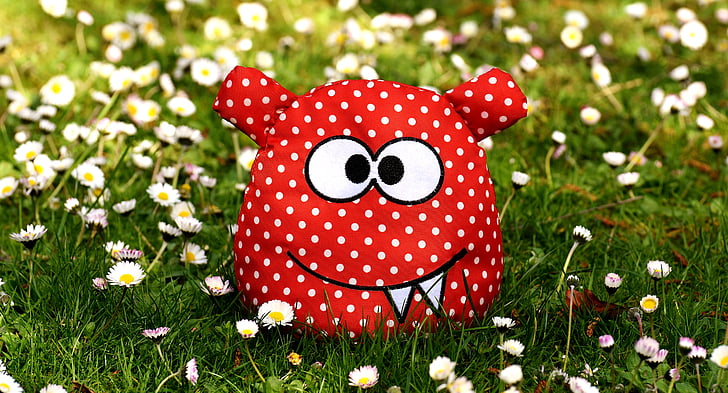plush toy on grass surrounded by flowers