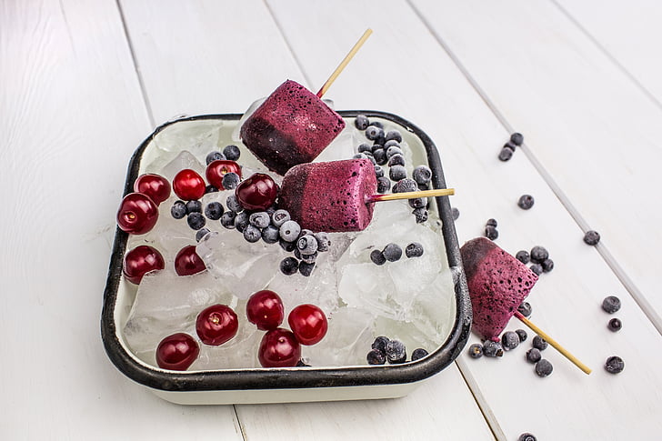 ice cubes with Popsicles and cherries in white bowl