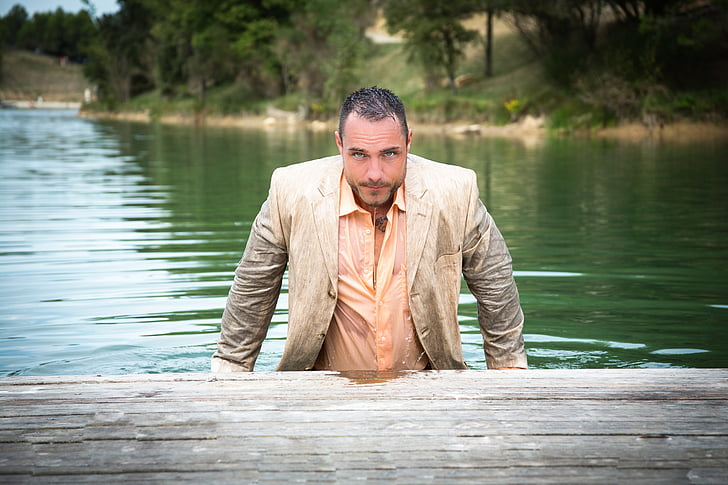 man in beige notched lapel suit on body of water