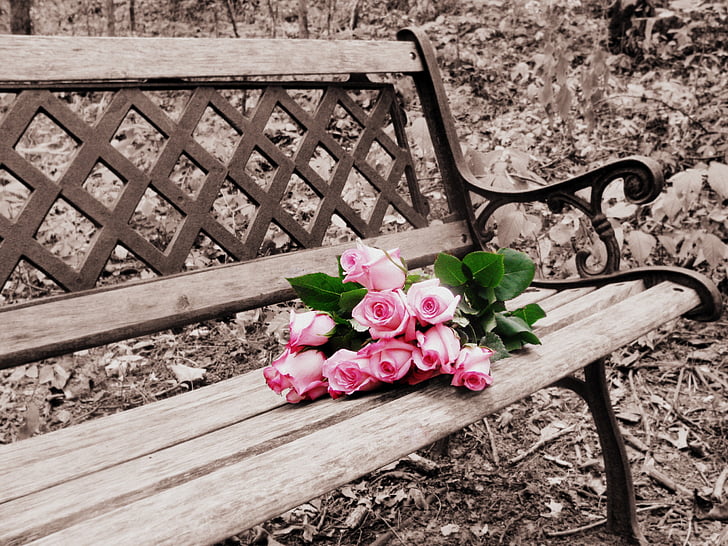 red rose arrangement on brown wooden bench