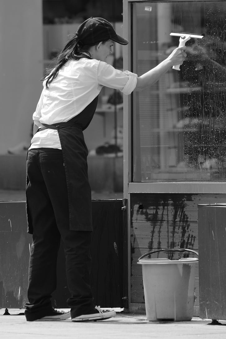 grayscale photography of woman cleaning window