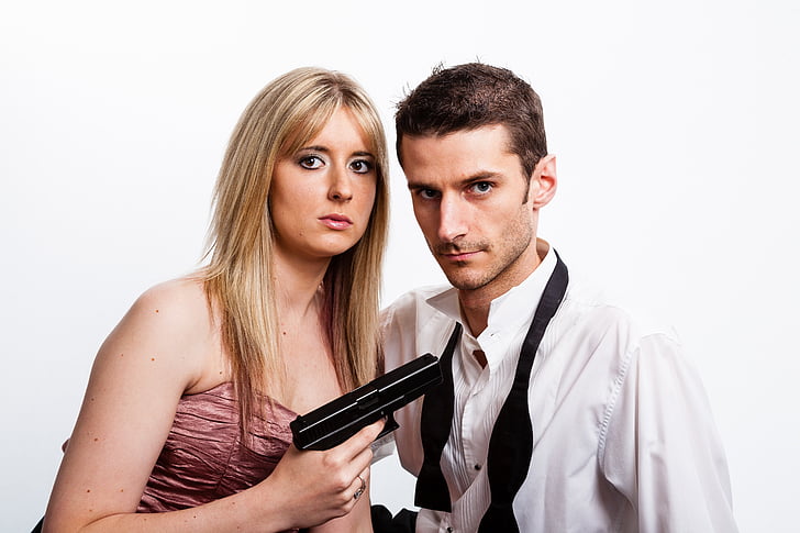 woman holding pistol while pointing at man beside