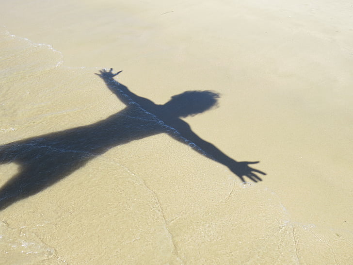 human shadow on beach sand during daytime