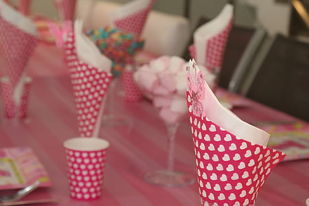 several napkin placed inside of pink heart print cone papers on top of table