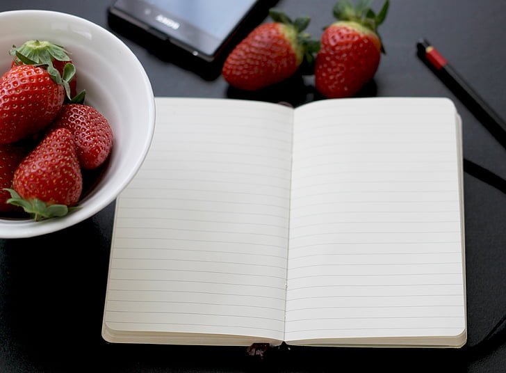 white notebook near strawberries