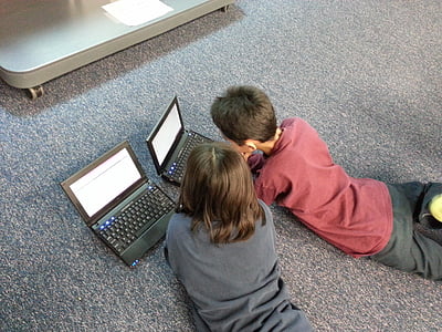 two boys wearing shirt infront laptop