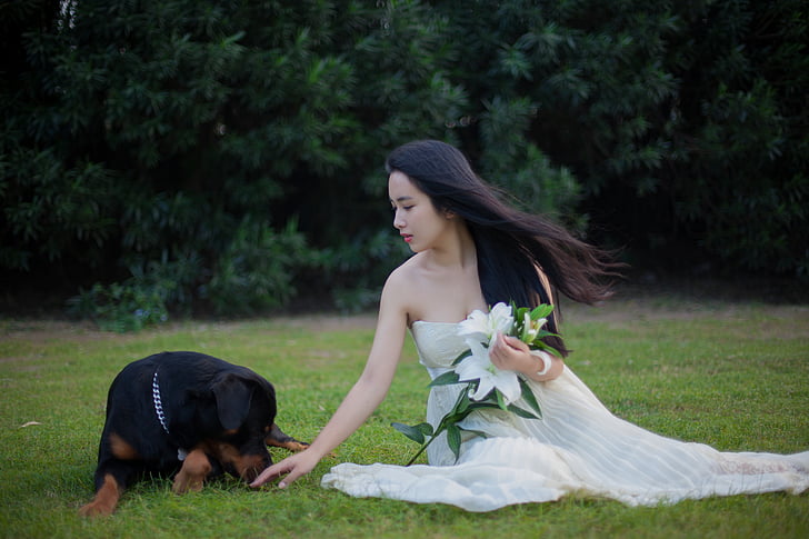 woman wearing tube dress beside Rottweiler dog