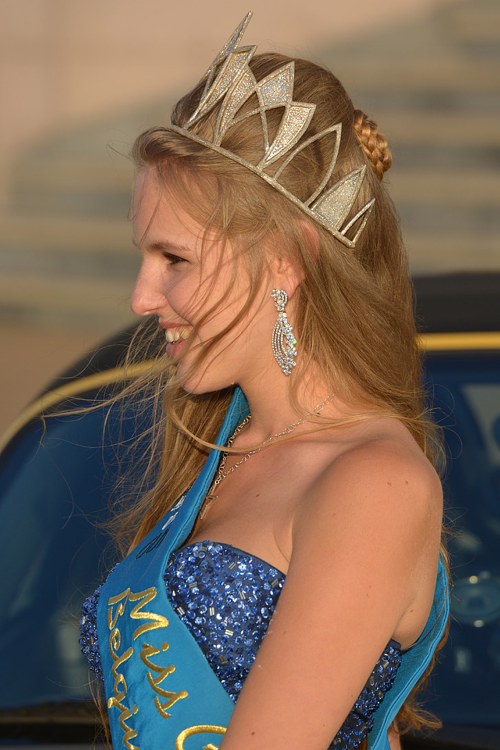 brown haired woman in blue dress with gold-colored tiara