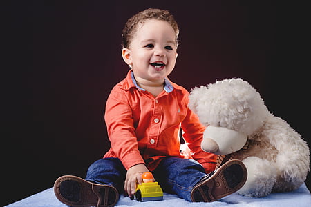 child sitting beside bear plush toy