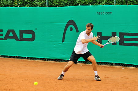 tennis player wearing white shirt looking at the ball bouncing