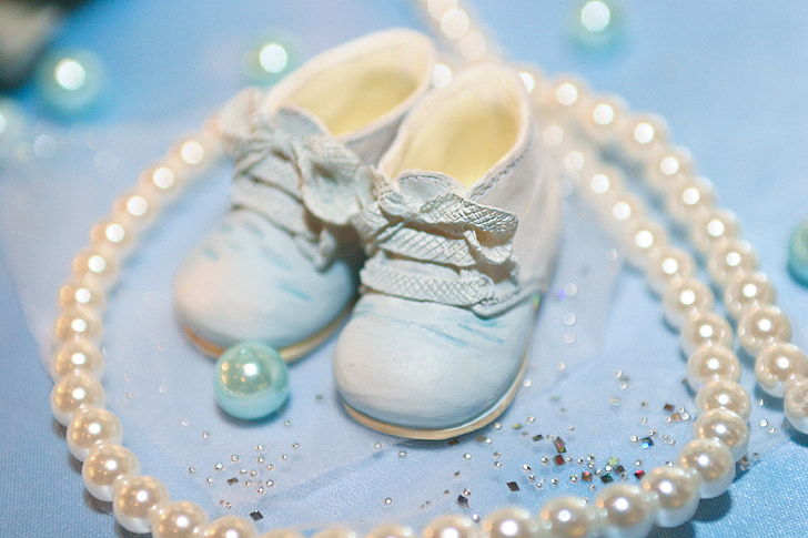 baby's white shoes surrounded by white pearls